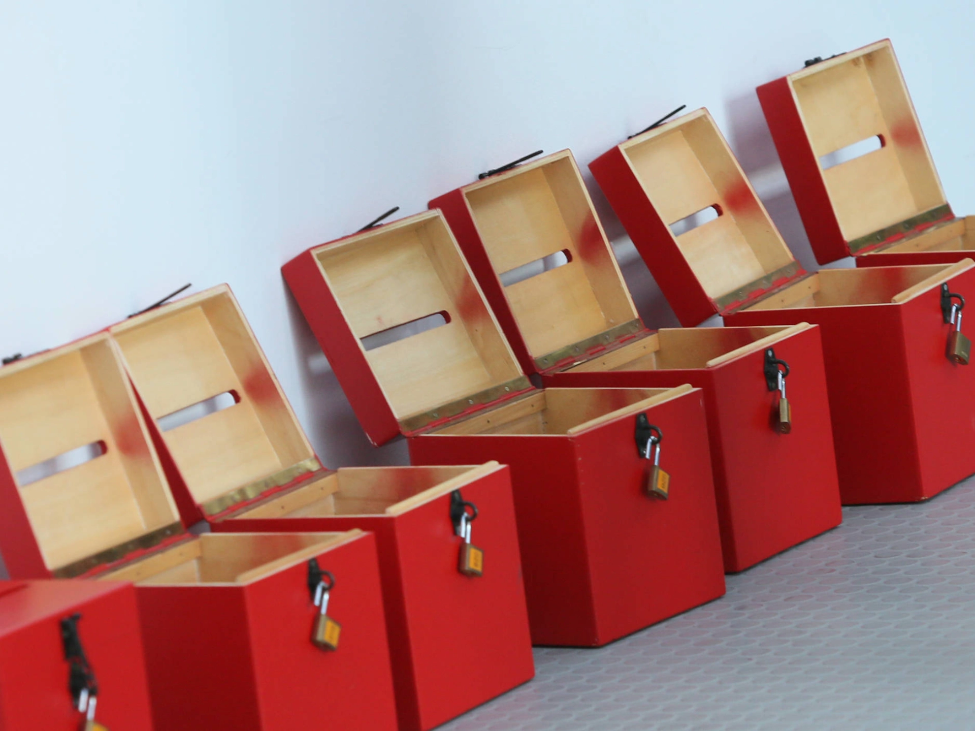 Offene Wahlurnen in rot stehen vor einer weißen Wand.